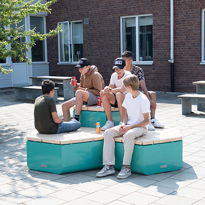 A group of young boys are relaxing and socialising on an outdoor rosenlund furniture combination in blue. It is like a hexagonal casual seating arrangement.